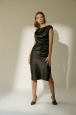 ZUMO FASHION satenska haljina rađena po meri sa blago prekrivenim ramenima, naborima koji oblikuju figuru i dubokim šlicem iznad kolena. Dostupna u četiri dužine, savršena je za svečane prilike i letnje proslave.