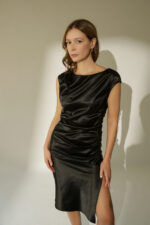 ZUMO FASHION satenska haljina rađena po meri sa blago prekrivenim ramenima, naborima koji oblikuju figuru i dubokim šlicem iznad kolena. Dostupna u četiri dužine, savršena je za svečane prilike i letnje proslave.