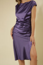 ZUMO FASHION satenska haljina rađena po meri sa blago prekrivenim ramenima, naborima koji oblikuju figuru i dubokim šlicem iznad kolena. Dostupna u četiri dužine, savršena je za svečane prilike i letnje proslave.